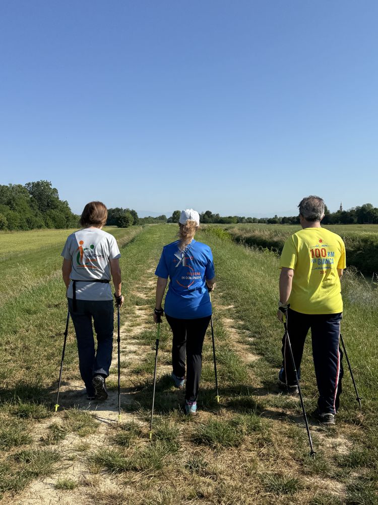 Tre persone camminano con i bastoncini lungo un sentiero di campagna